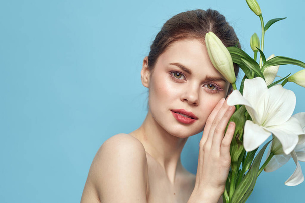 mooi meisje met een boeket van witte bloemen op een blauwe achtergrond  - Foto, afbeelding