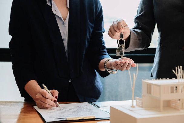 Makler übergibt Hausschlüssel an Mann und unterschreibt Vertrag im Büro - Foto, Bild
