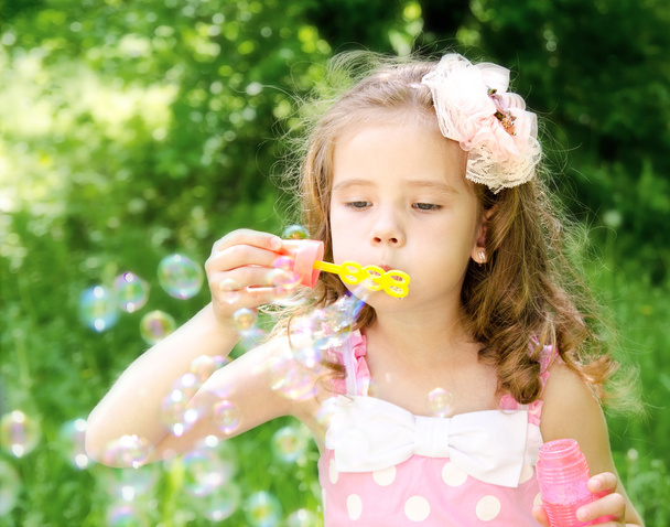 Cute little girl is blowing a soap bubbles - Photo, Image