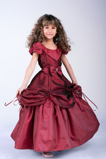 Красивая маленькая девочка танцует в винно-красном платье
 - Фото, изображение