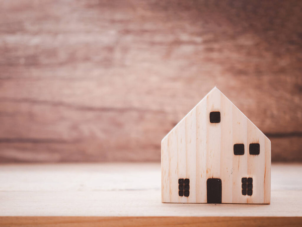 Model domu na drewnianym tle. Ubezpieczenie inwestycyjne i koncepcja hipoteki na zakup domu - Zdjęcie, obraz