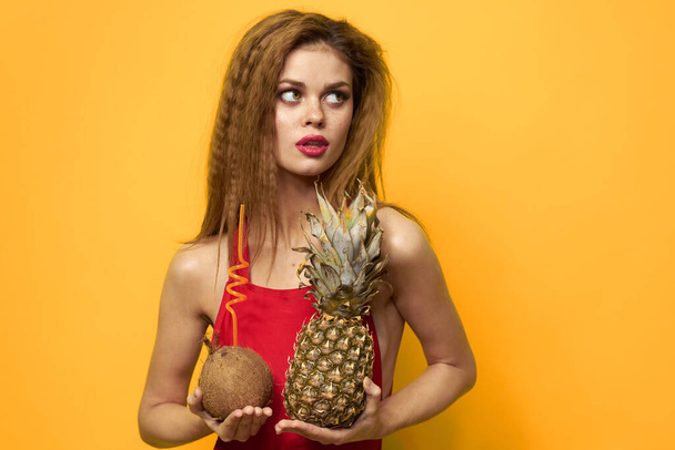 mujer con piña y coco cóctel frutas exóticas estilo de vida de verano fondo amarillo - Foto, Imagen