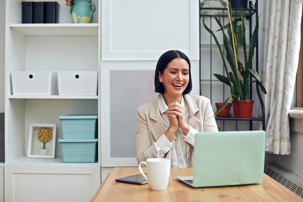 junge Frau mit Laptop und Kaffeetasse auf Tisch im Büro - Foto, Bild