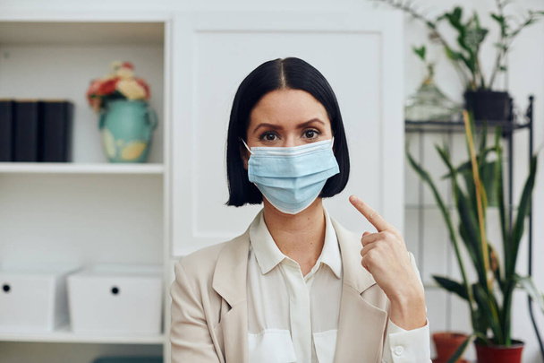 νεαρή γυναίκα με ιατρική μάσκα και προστατευτικές μάσκες προσώπου στο γραφείο - Φωτογραφία, εικόνα