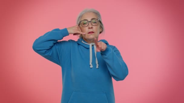 Senior Oma grauhaarige Frau schaut in die Kamera dabei Handygeste wie sagt hey Sie rufen mich zurück - Filmmaterial, Video