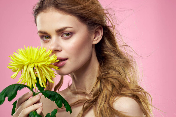 Portrét ženy se žlutou květinou na růžovém pozadí Make-up na tváři. Kvalitní fotografie - Fotografie, Obrázek