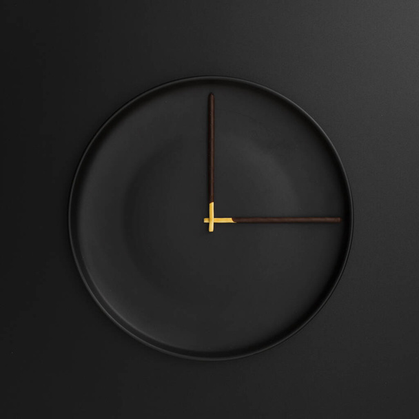 σκούρο πιάτο με σοκολατένια ραβδιά σχηματίζουν ρολόι. Ανάλυση και υψηλής ποιότητας όμορφη φωτογραφία - Φωτογραφία, εικόνα