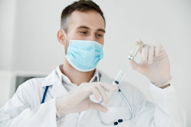 médico en el laboratorio sostiene una jeringa en su mano máscara médica vacuna líquido - Foto, Imagen