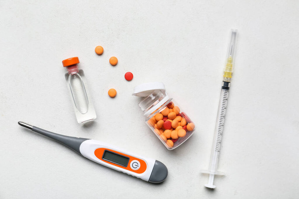 Ηλεκτρονικό θερμόμετρο με χάπια, εμβόλιο και σύριγγα σε λευκό φόντο - Φωτογραφία, εικόνα