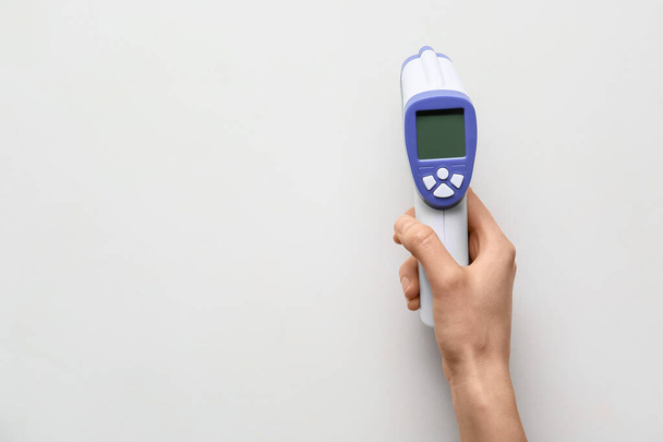 Vrouwelijke hand met infrarood thermometer op witte achtergrond - Foto, afbeelding