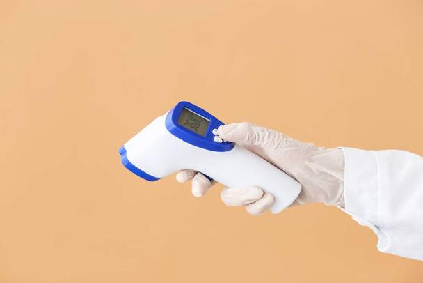 Ręka lekarza z termometrem na podczerwień na tle koloru - Zdjęcie, obraz
