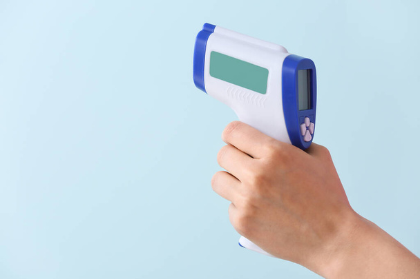 Female hand with infrared thermometer on color background - Photo, Image