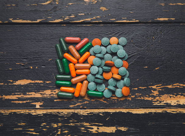Различные таблетки на темном деревянном фоне - Фото, изображение