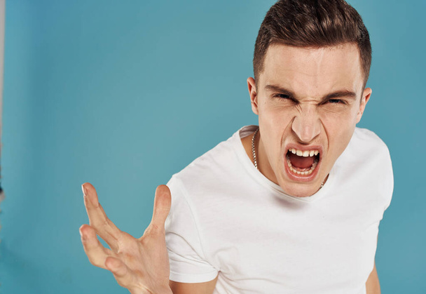Angry man in white t-shirt gesture with hands displeasure blue background - Photo, Image