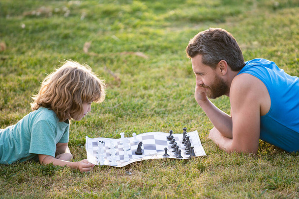 Father and son playing chess spending time together outdoor. - Zdjęcie, obraz