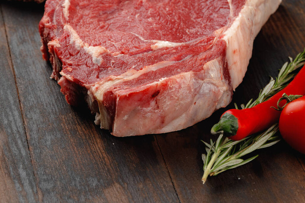 Raw rib eye steak on brown wooden board - Фото, зображення