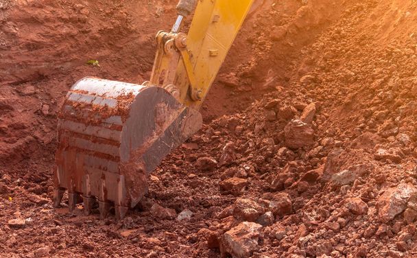 Backhoe working by digging soil at construction site. Bucket of backhoe digging soil. Crawler excavator digging on dirt. Closeup backhoe bucket of yellow backhoe. Earthmoving. Trenching machine. - Photo, Image