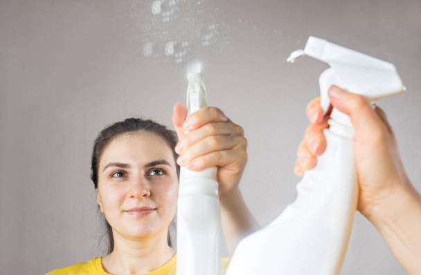 A takarítónő egy vízadagolóval és ablaktisztítóval tisztítja meg a tükröt. Takarítás. Takarítási szolgáltatás - Fotó, kép