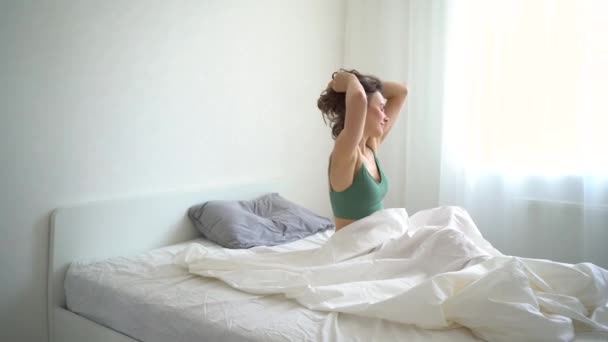 Enjoying a sunny morning in bed. The girl wakes up in the morning and stretches. Morning awakening of a girl in bed. - Footage, Video