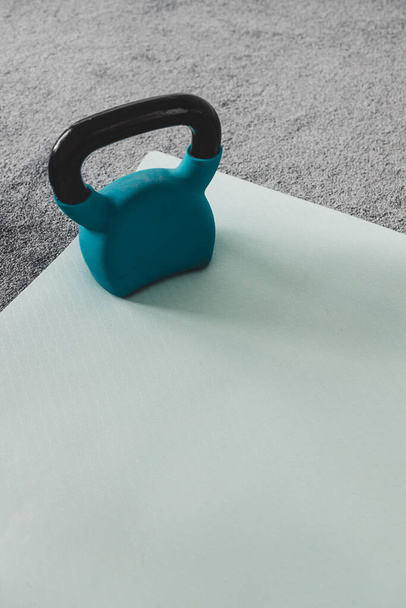 home gym with mixed fitness items including yoga mat and kettlebell with subtle grey and blue tones  - Foto, Bild