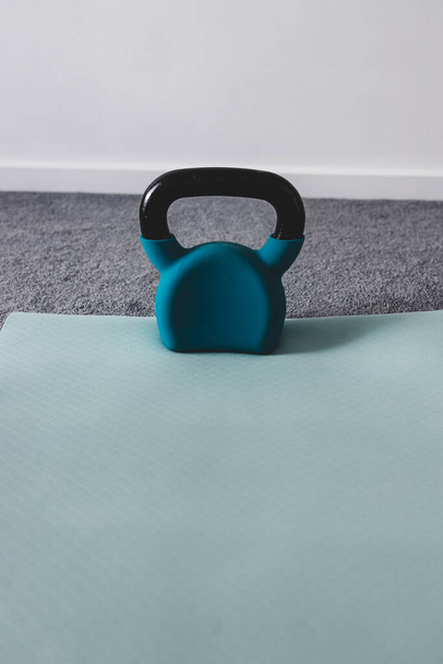 home gym with mixed fitness items including yoga mat and kettlebell with subtle grey and blue tones  - Φωτογραφία, εικόνα