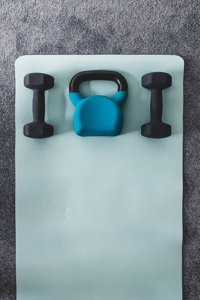 kettlebell and dumbbells on yoga mat indoor, concept of home gym and weight training styled with subtle grey and blue tones  - Φωτογραφία, εικόνα