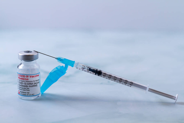 Valencia, Spanyolország 2021. április 21. A MODERNA vállalattól származó COVID-19 vírus elleni vakcina injekciós üvege a beteg oltásához szükséges adaggal töltött fecskendővel. - Fotó, kép