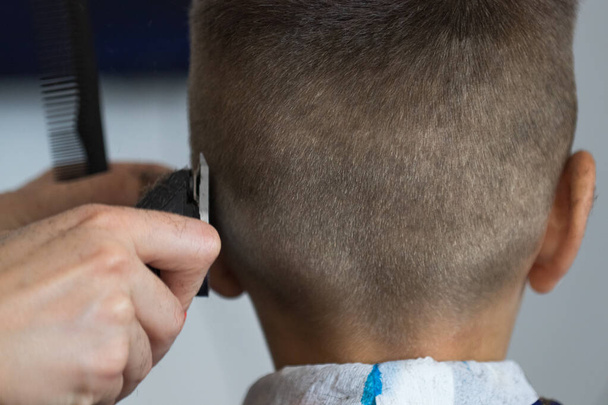 Coupe de cheveux pour hommes avec une tondeuse dans un coiffeur. Peigne, coiffure, soins, salon, coiffeur, service, salon de coiffure - Photo, image