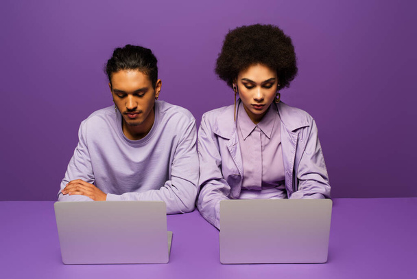 jong Afrikaans Amerikaans paar met behulp van laptops geïsoleerd op paars  - Foto, afbeelding