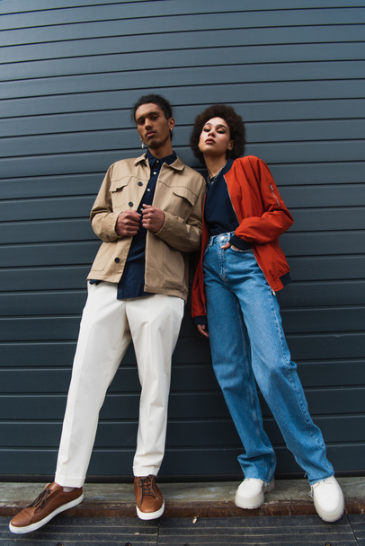low angle view of young african american man posing with stylish woman standing with hand in pocket - Fotó, kép