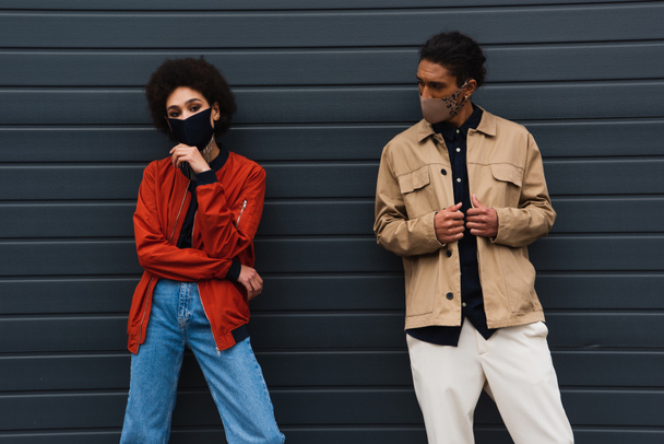 young african american woman and stylish man in protective masks posing outdoors  - Photo, Image
