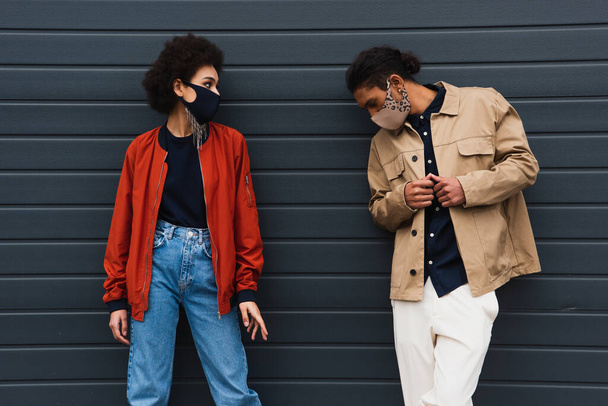 young african american woman and man in stylish protective masks posing outside - Фото, зображення