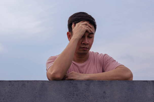 Aziatische ellendige depressieve man blijf alleen met lucht achtergrond. Depressie en concept van geestelijke gezondheid. - Foto, afbeelding