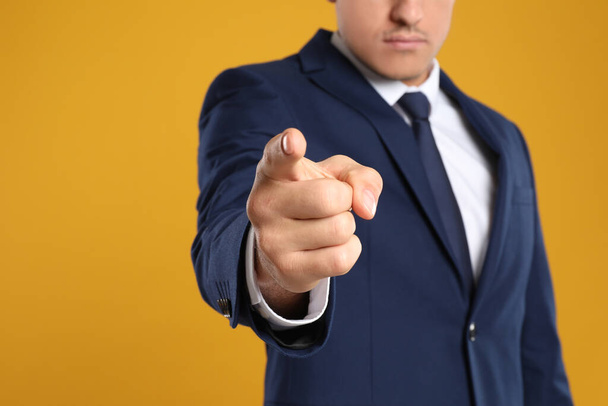 Businessman touching something on yellow background, closeup. Finger gesture - 写真・画像