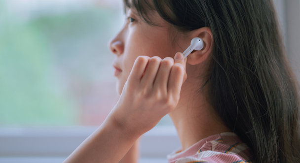 junge Asiatin benutzt drahtlose Kopfhörer, um Musik zu hören - Foto, Bild
