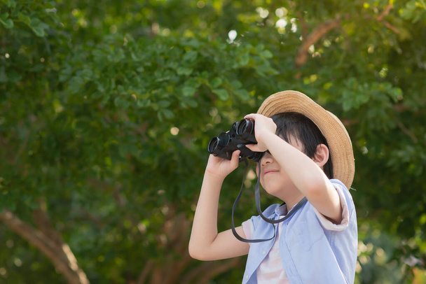 lindo asiático niño holding binoculares al aire libre en soleado verano día - Foto, Imagen