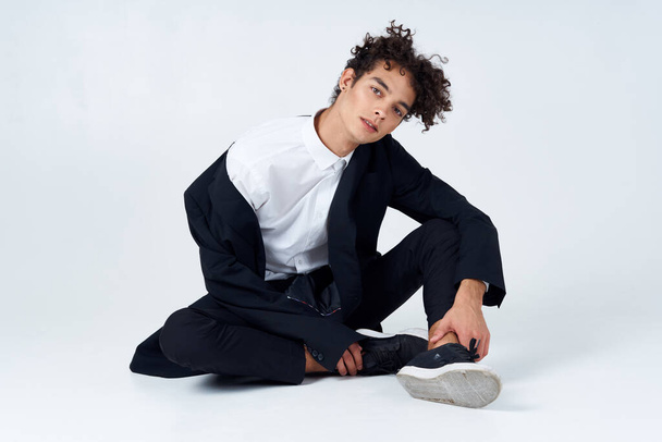 tipo sentado en el suelo rizado pelo traje moderno estilo aislado fondo - Foto, Imagen