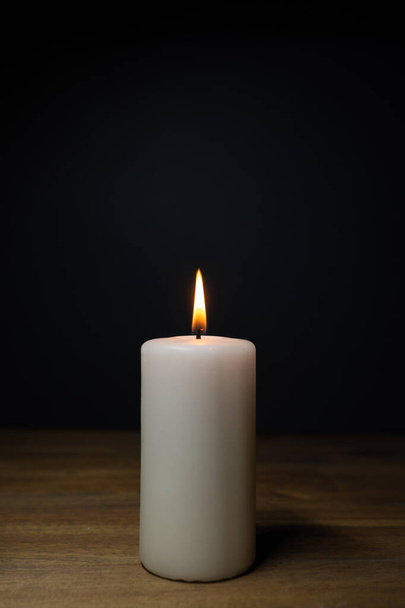 Bílá hořící svíčka na dřevěném stole, tmavé pozadí a kopírovat prostor - Fotografie, Obrázek