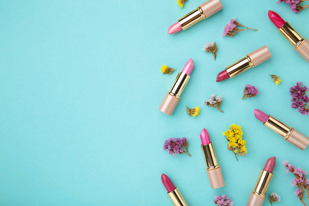Lipstick with beautiful flowers on blue background. Top view - Fotó, kép
