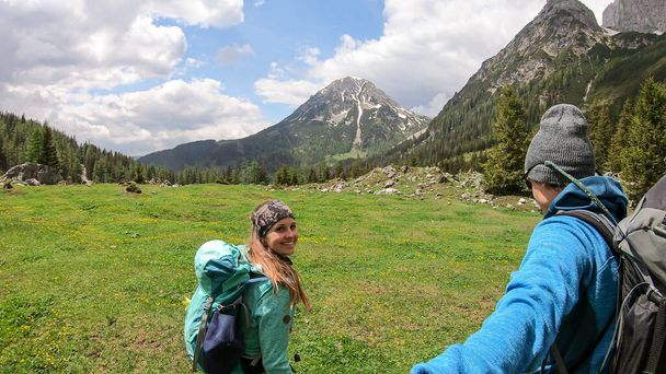 Una coppia di escursionisti escursionisti attraverso un lussureggiante prato nella valle fino alla vetta di Marstein nelle Alpi austriache. Montagne rocciose e taglienti. Nuvoloso. Pendii di Baren, fitta foresta ai piedi. Felicità - Foto, immagini
