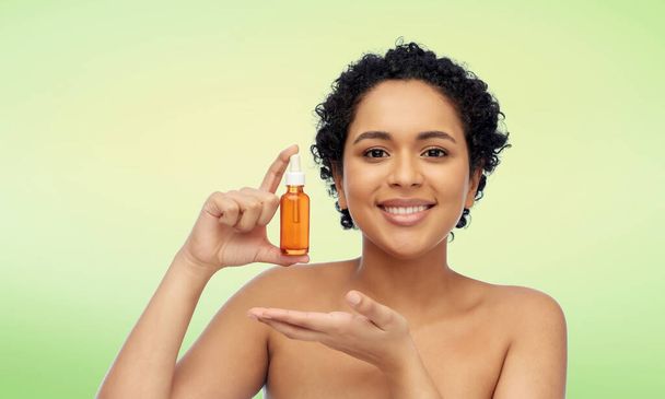 happy african american woman with bottle of serum - Foto, immagini