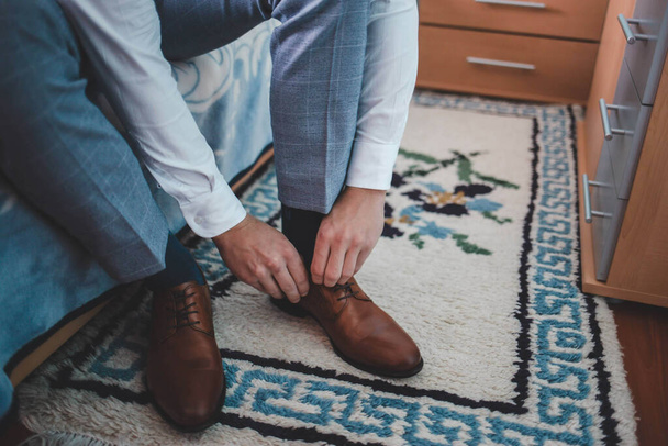 Крупный план хорошо одетого мужчины, завязывающего кожаные шнурки - Фото, изображение