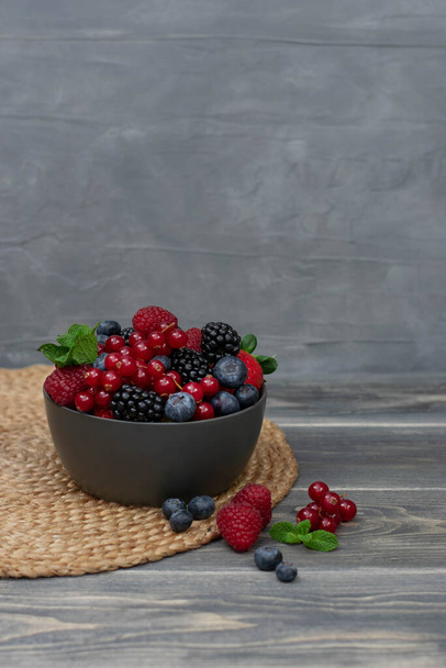 Ripe sweet different berries in bowl on wooden table. Harvest Concept. Fresh berries. - Foto, imagen