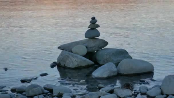 Equilíbrio pilha zen pedra perto do lago durante o pôr do sol. - Filmagem, Vídeo