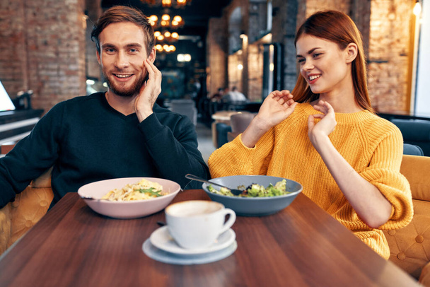 Bir adam ve bir kadın restoranda bir masada oturmuş lezzetli yemekler servis ediyorlar. - Fotoğraf, Görsel
