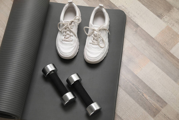 Dumbbells, sneakers and mat on wooden floor, above view - Photo, Image