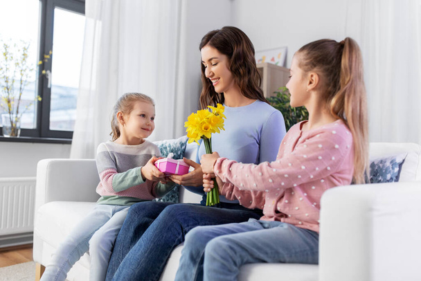 daughters giving flowers and gift to happy mother - Фото, зображення