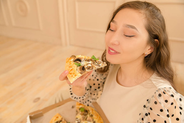 Young woman student eating pizza at home, close up - Foto, imagen