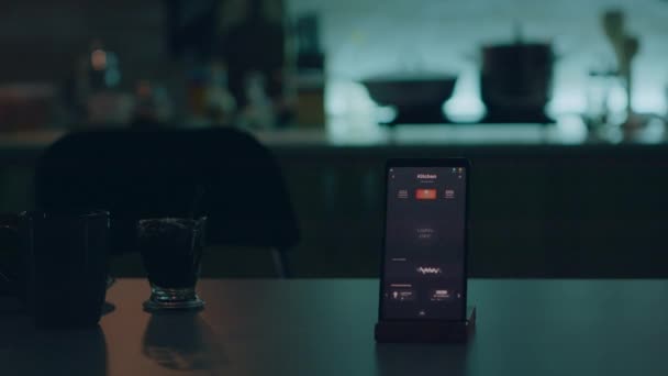 Smart home applicatie op telefoon geplaatst op keukenbureau in leeg huis - Video