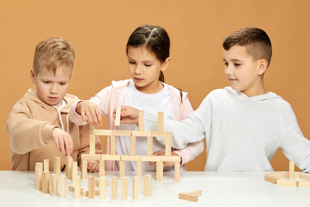 children plays with wooden constructor on desk. - Foto, Imagen